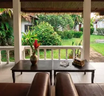 A porch table with a red flower, looking out to the lawn