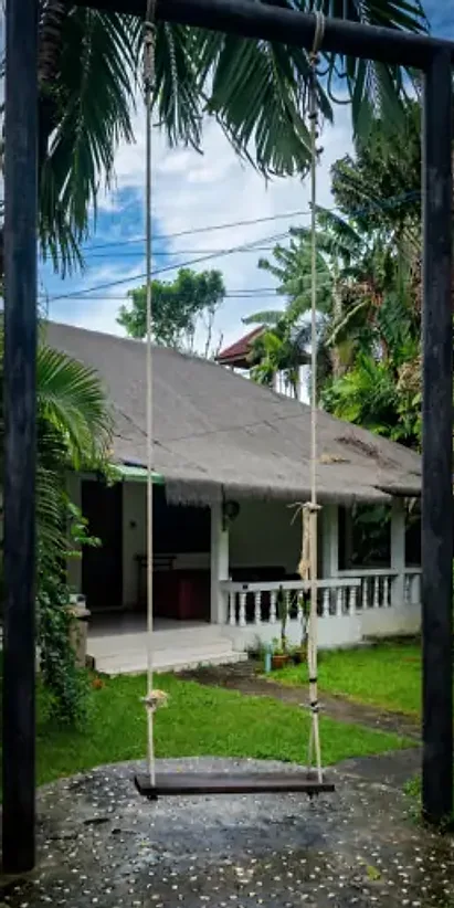 A rope swing hanging between two posts in front of a cottage